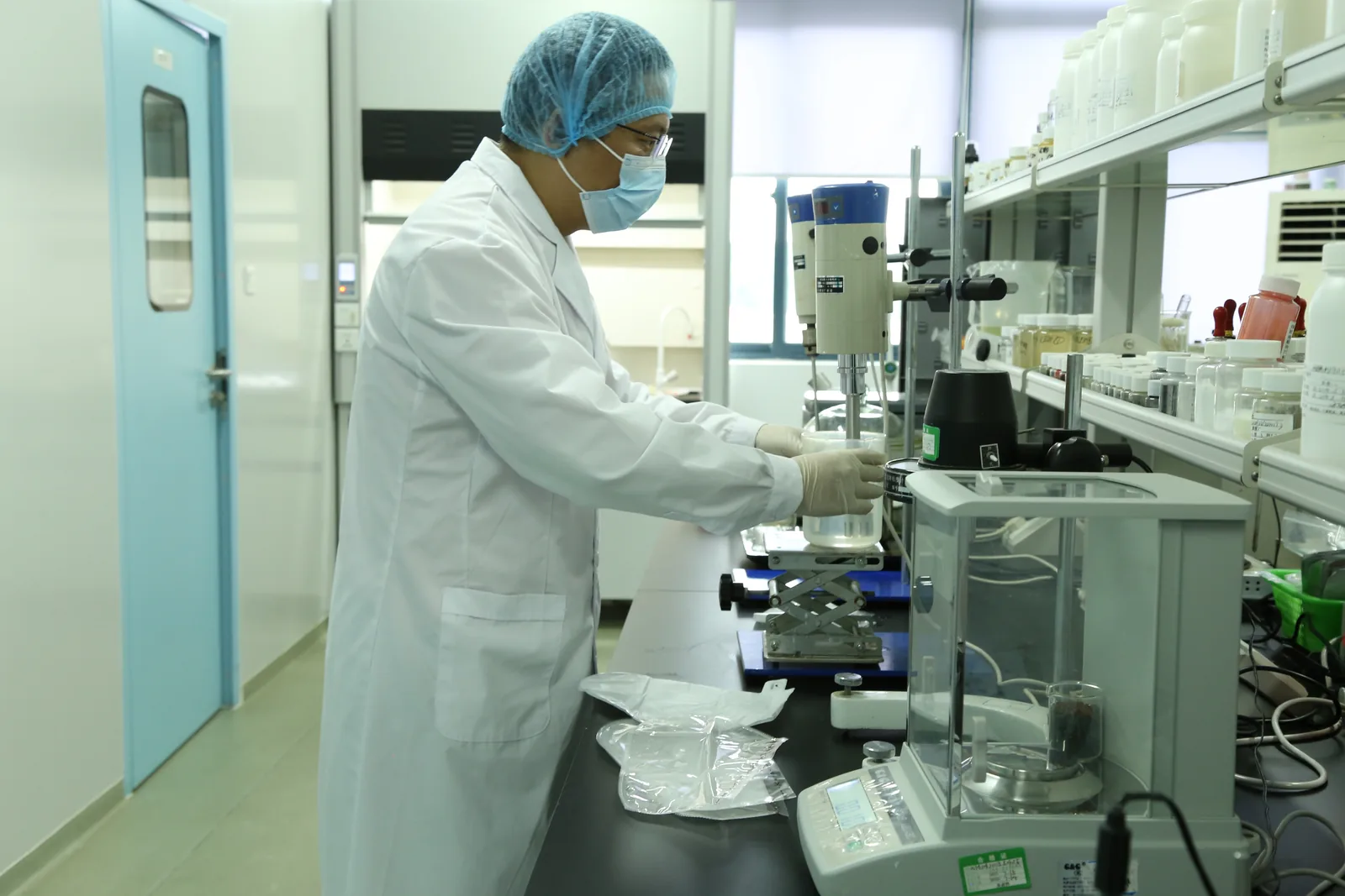 Chemist operating analytical instruments on cosmetic formulation samples